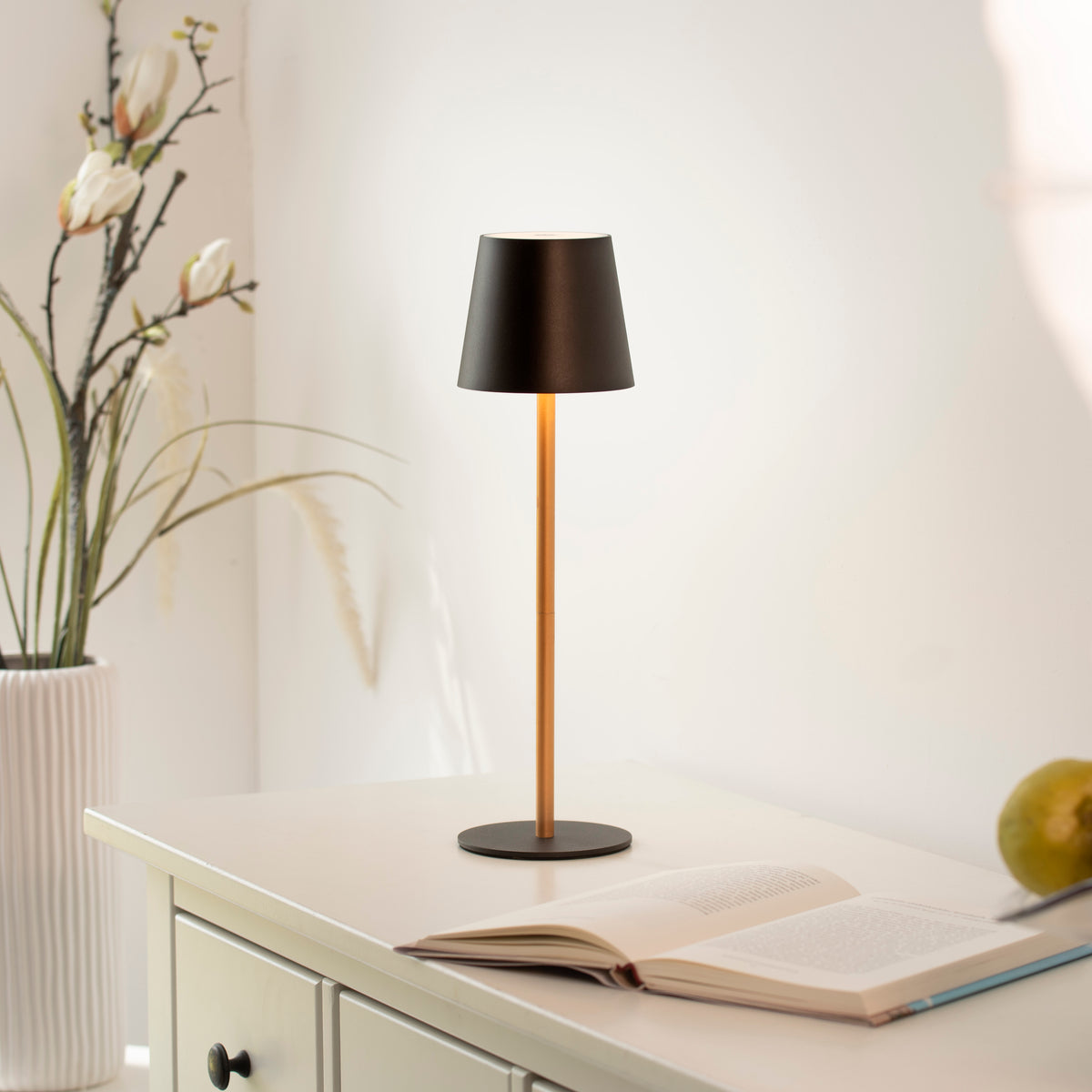 Mise en ambiance : lampe posée sur un meuble blanc près d'un livre ouvert.