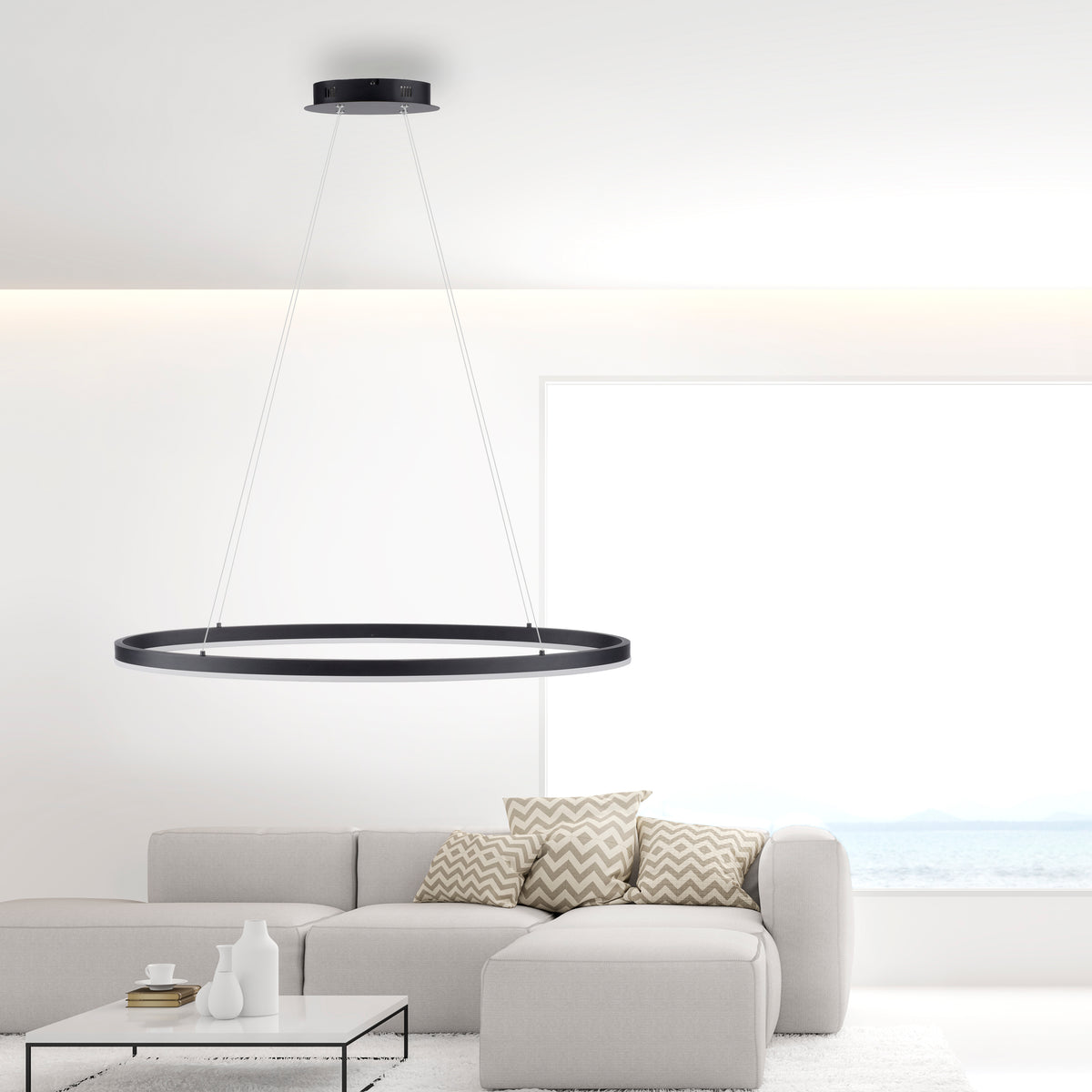 Mise en ambiance dans un salon avec canapé, coussins et suspension allumée.