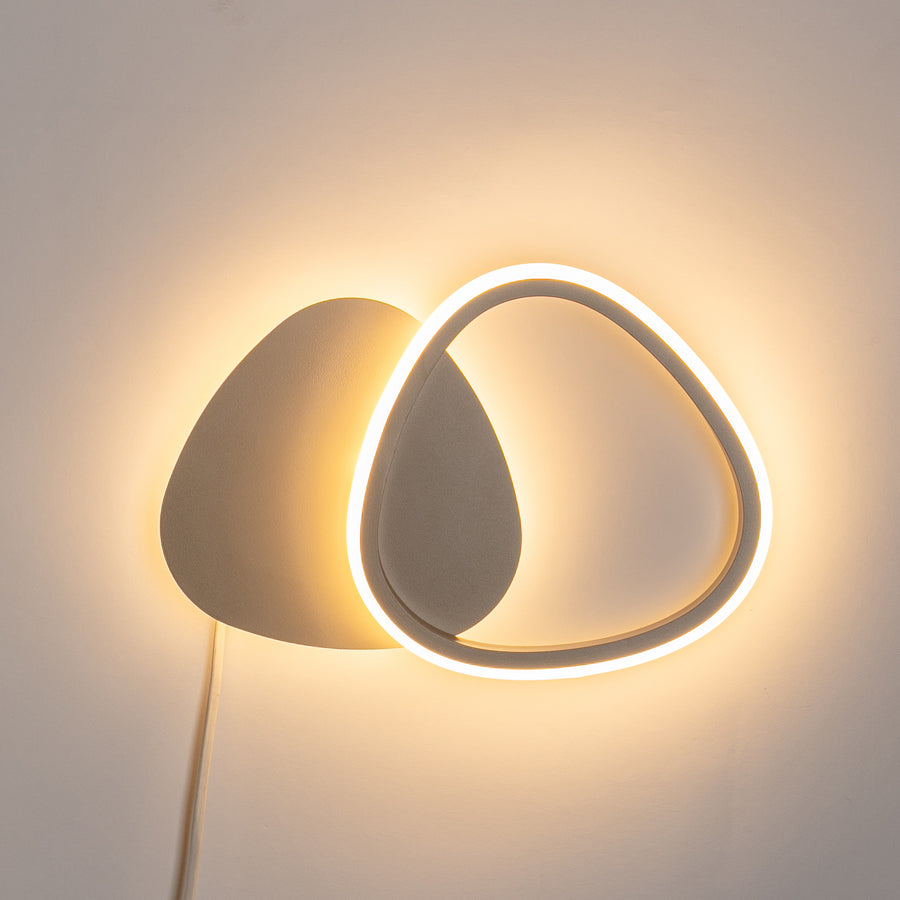 Applique allumée sur un mur blanc, anneau lumineux diffusant une lumière chaude