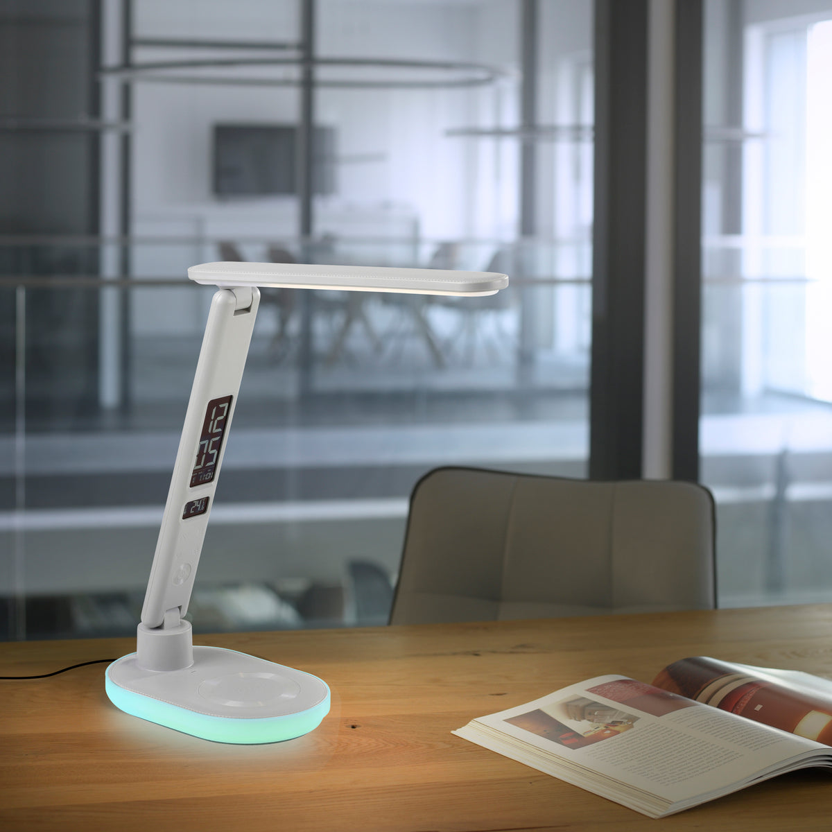 Lampe posée sur bureau en bois près d'un magazine ouvert, socle lumineux cyan.