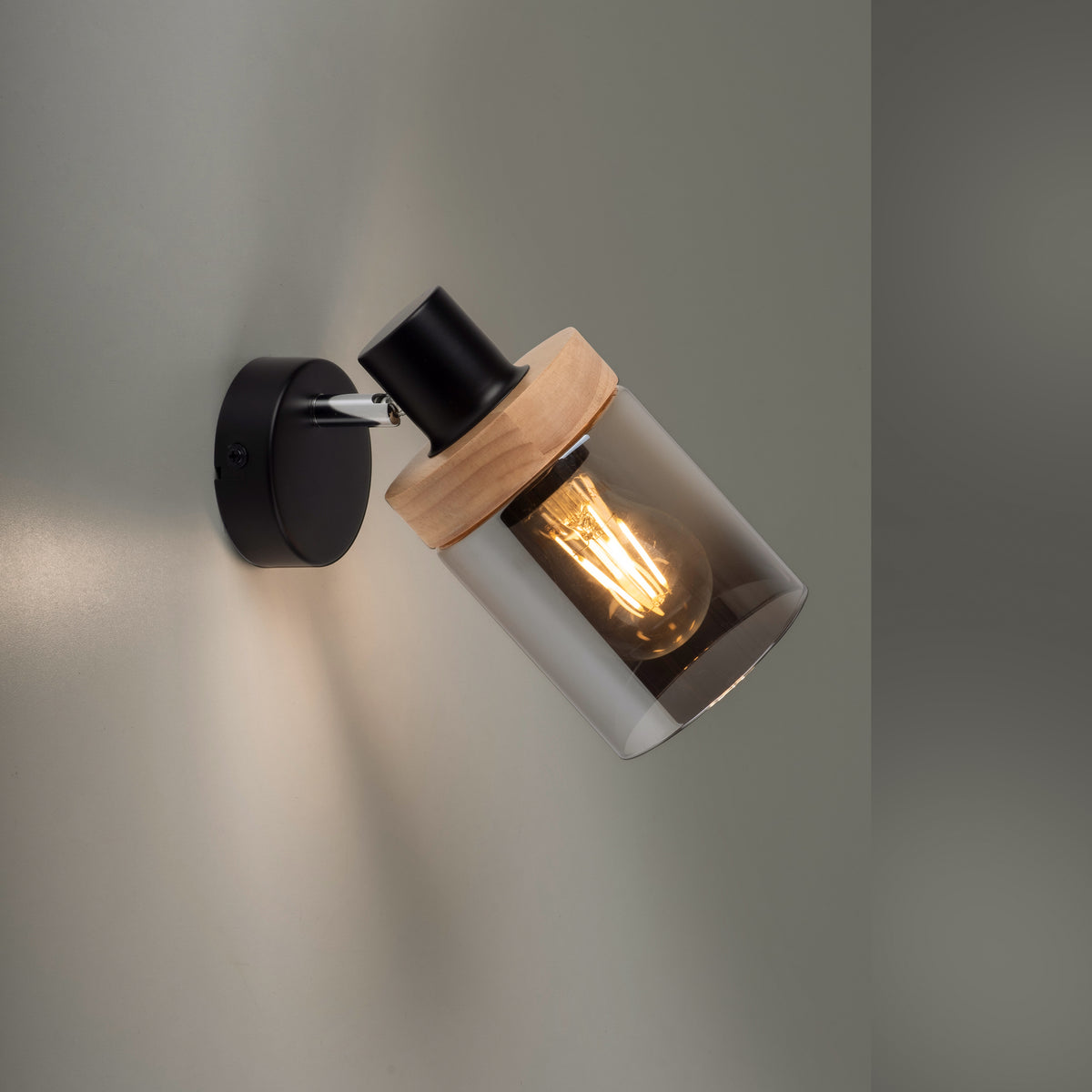 Gros plan du luminaire allumé diffusant une lumière chaude sur un mur gris
