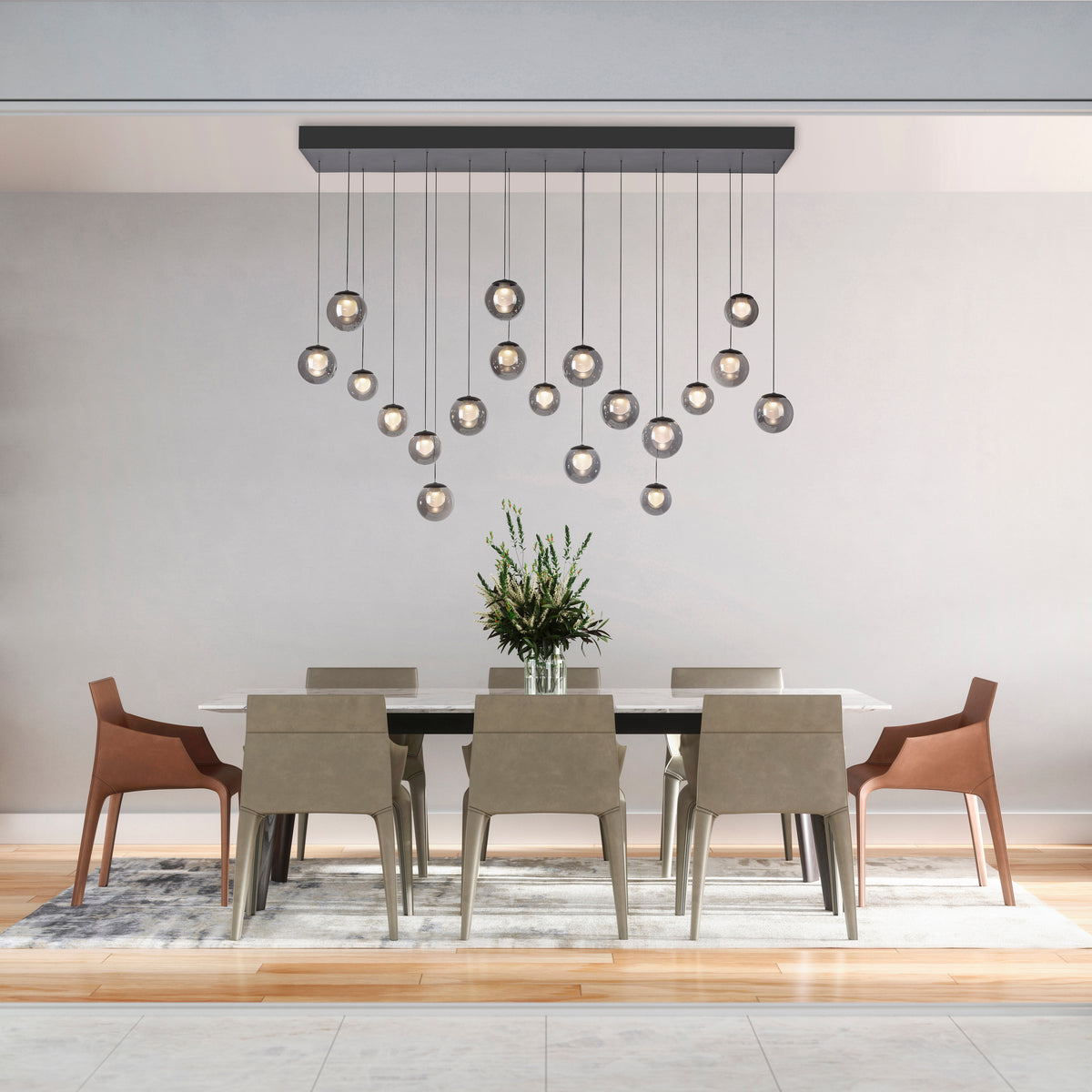 Suspension allumée au-dessus d'une table blanche avec chaises beiges et plante.