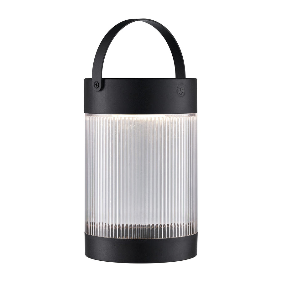 Vue de face du luminaire allumé, diffuseur cylindrique en verre strié émettant une lumière chaude.