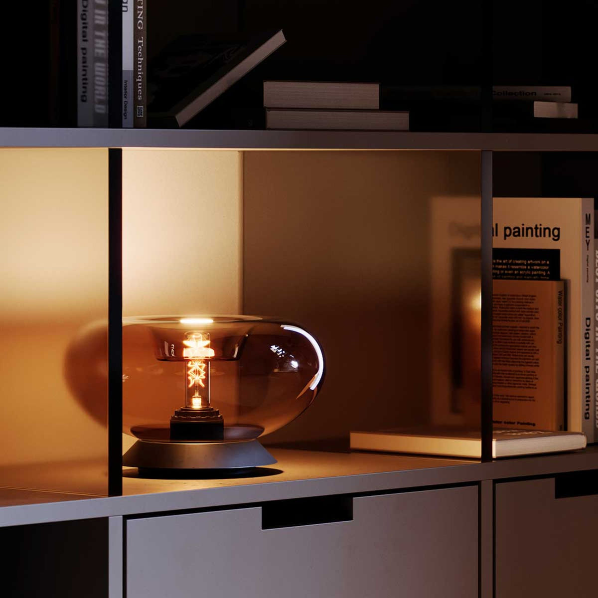 Détail de la lampe ovale posée dans une niche d'étagère, reflets chauds sur le verre