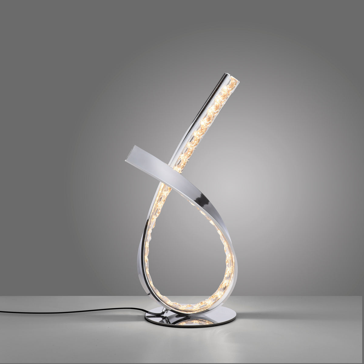 Luminaire allumé posé sur surface grise, câble d'alimentation visible