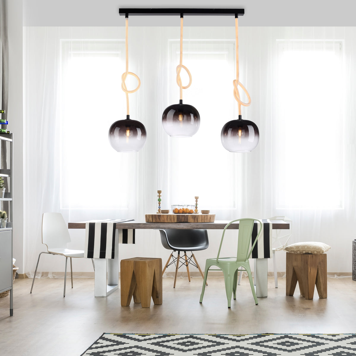 Suspension installée au-dessus d'une table de salle à manger dans un intérieur lumineux.