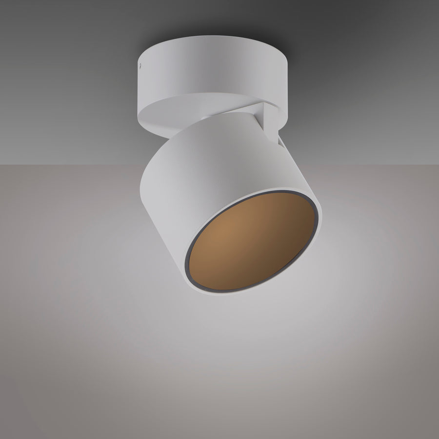 Vue de trois quarts du plafonnier blanc orientable avec intérieur doré et lumière allumée.