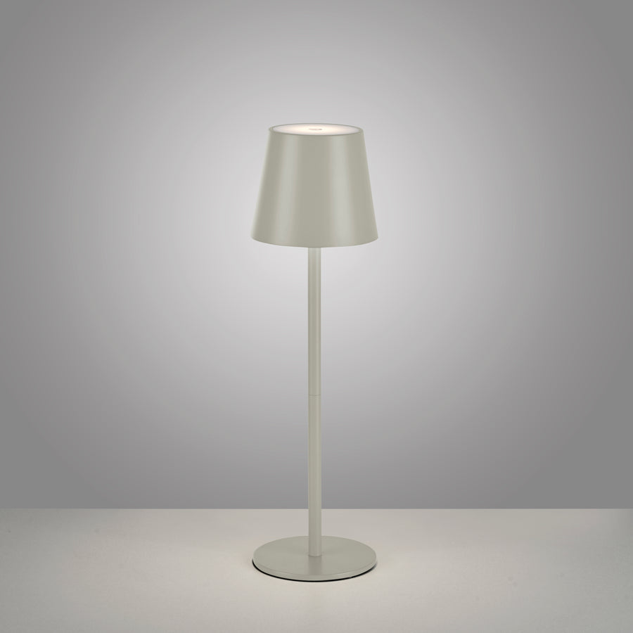 Lampe à poser éclairée sur fond gris, mettant en valeur la base ronde et le piétement.