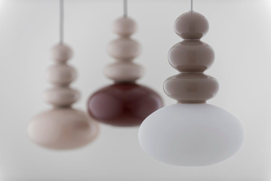 Trois suspensions en gros plan, nettes et floues, beige, bordeaux et blanc.