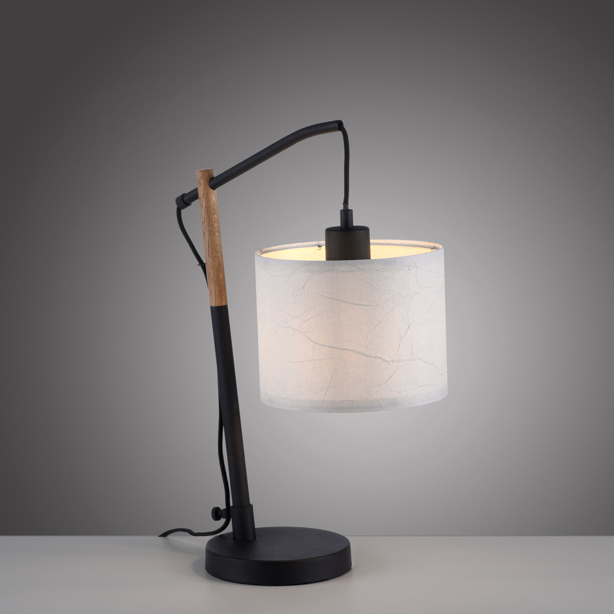 Lampe à poser sur fond gris dégradé, abat-jour cylindrique blanc allumé, vue de face