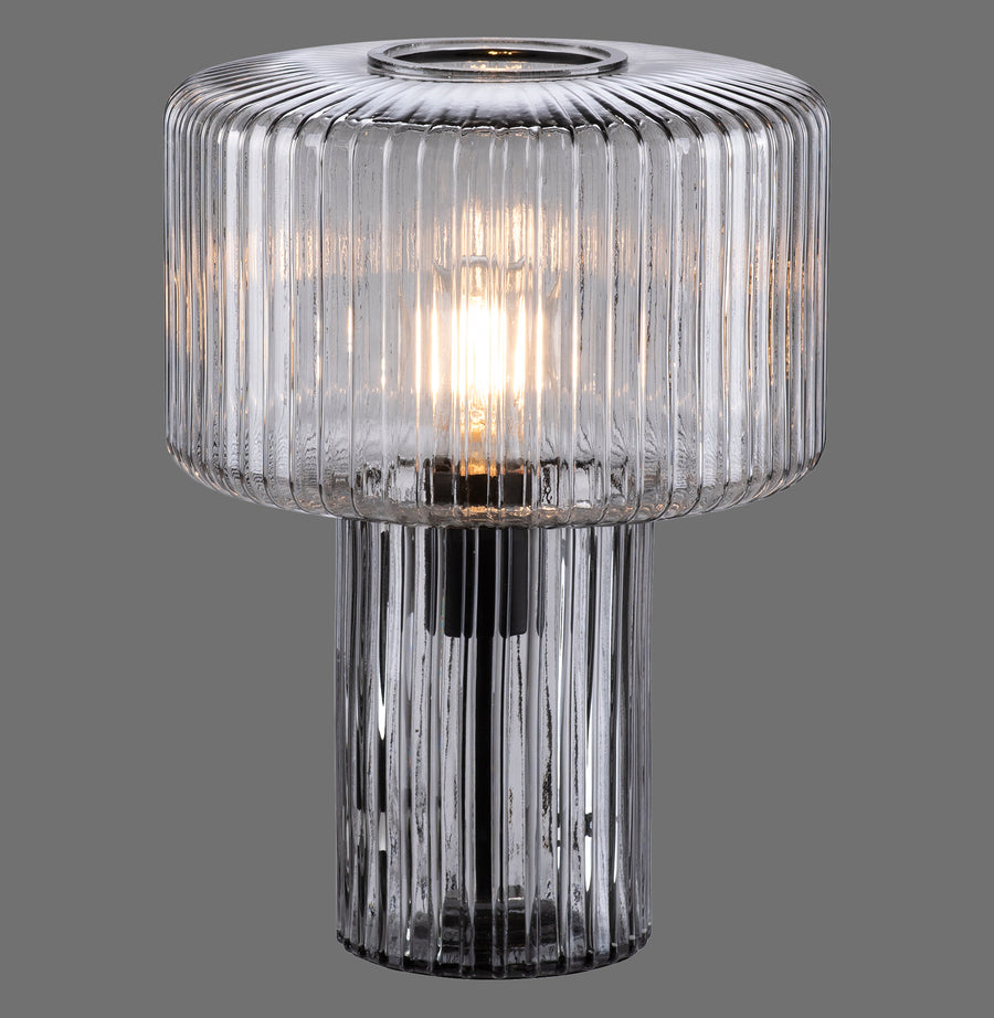 Lampe à poser en verre fumée côtelé, face avant allumée, fond gris anthracite.
