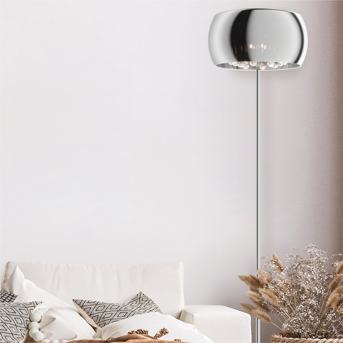 Mise en ambiance du lampadaire chromé près d'un canapé blanc et coussins à motifs.