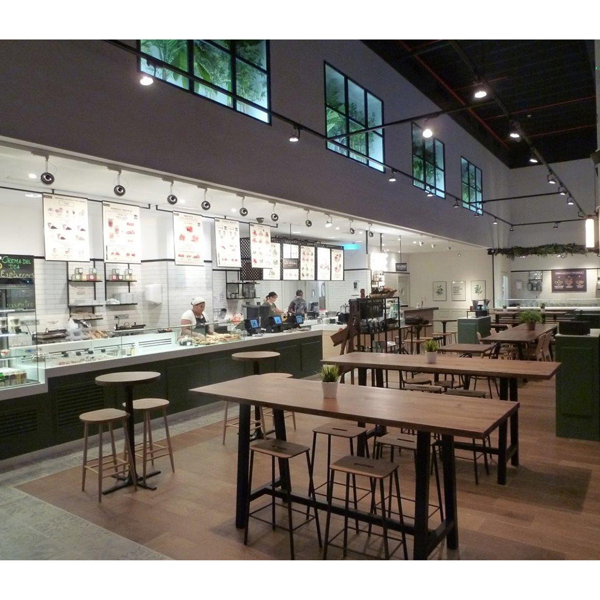 Ambiance de café-restaurant avec spots sur rail au plafond éclairant le comptoir et les tables.