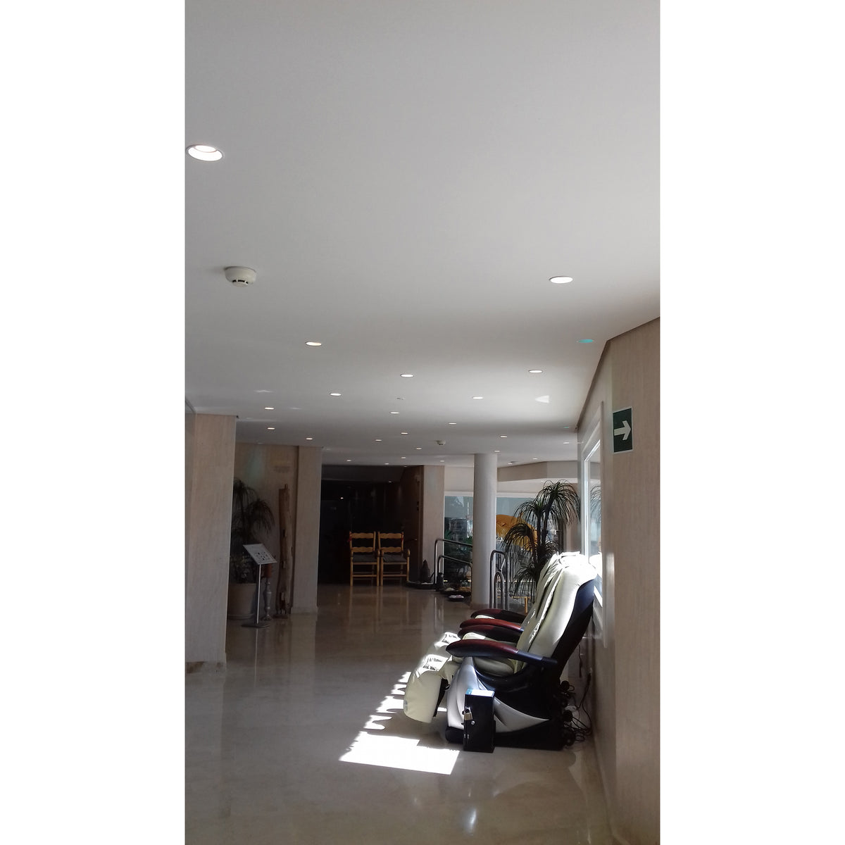 Couloir éclairé par plusieurs spots encastrés au plafond, ambiance sobre