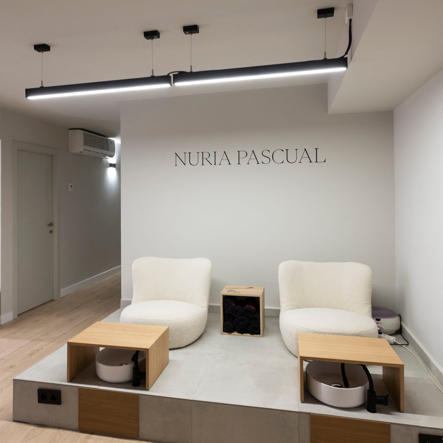 Suspension allumée éclairant un espace d'accueil avec fauteuils et présentoirs