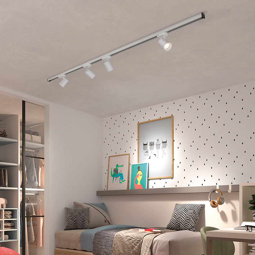 Mise en ambiance dans une chambre, rail blanc au plafond avec quatre spots orientés.