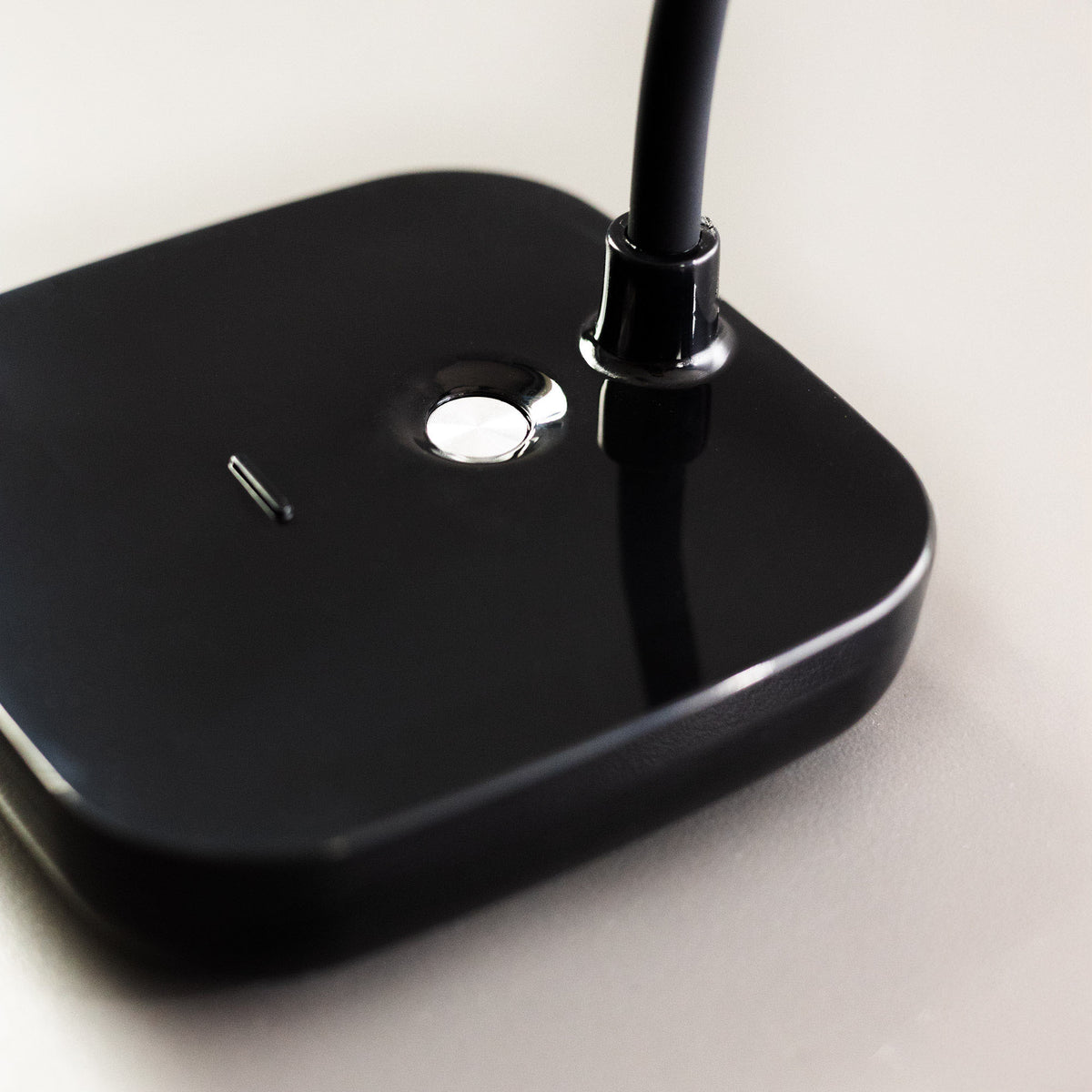 Gros plan sur la base noire brillante avec bouton tactile et fixation du col.