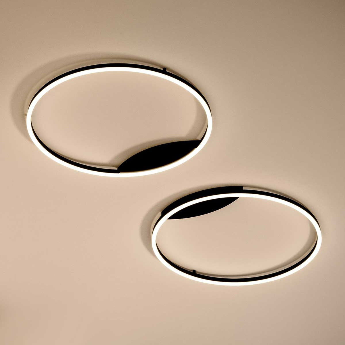 Deux plafonniers circulaires noirs et blancs vus de dessous sur fond beige
