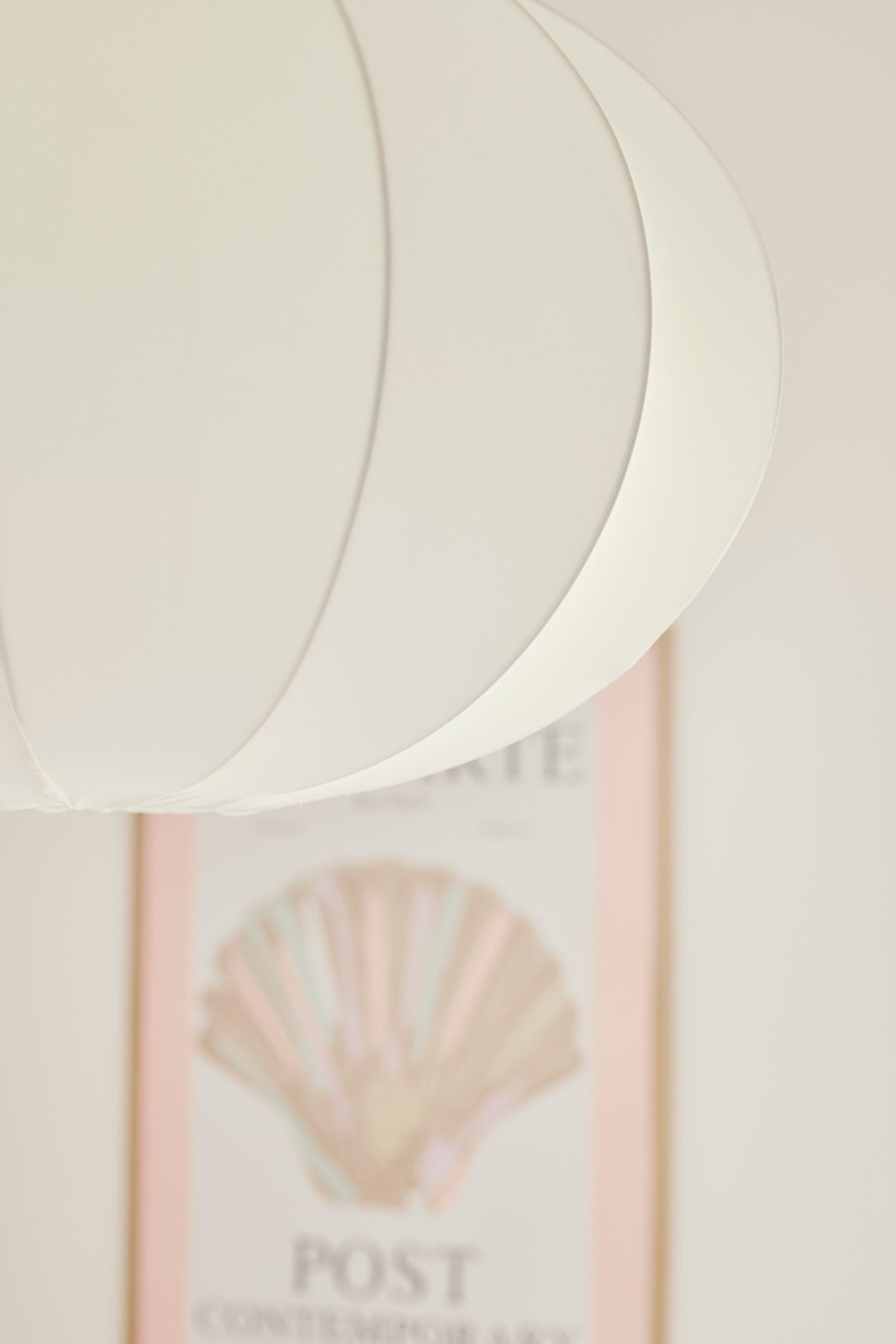 Mise en ambiance du luminaire allumé devant une affiche encadrée dans un intérieur doux