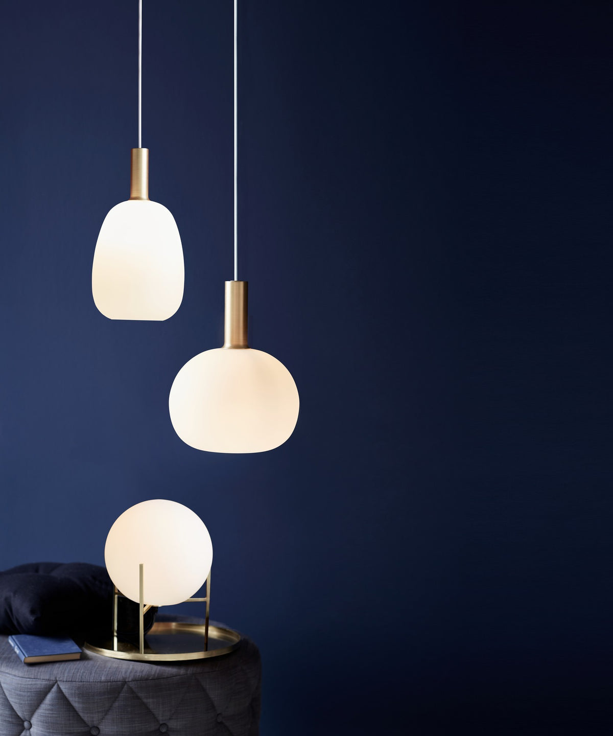 Lampe à poser allumée sur un plateau doré, suspensions en arrière-plan.