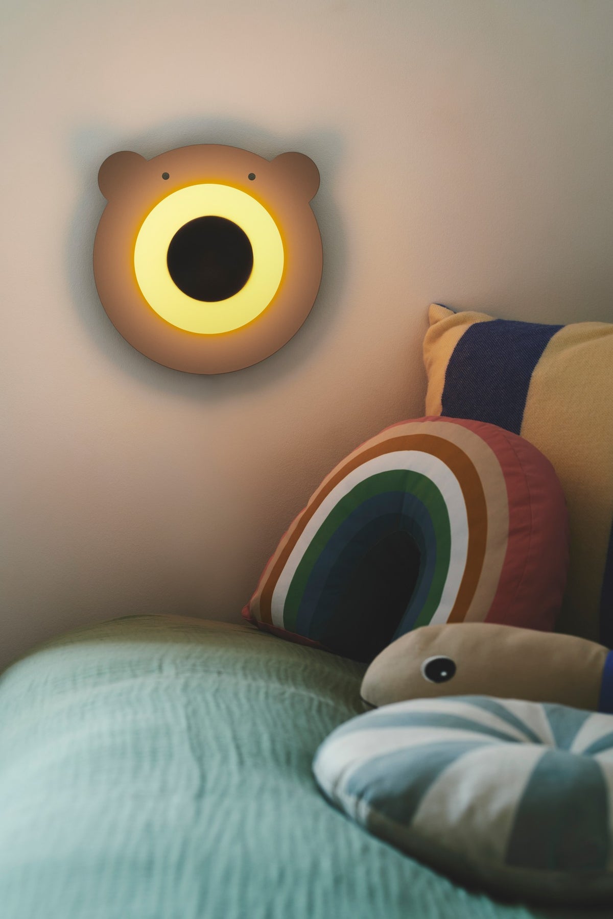 Gros plan sur l'applique allumée diffusant une lumière chaude près du lit