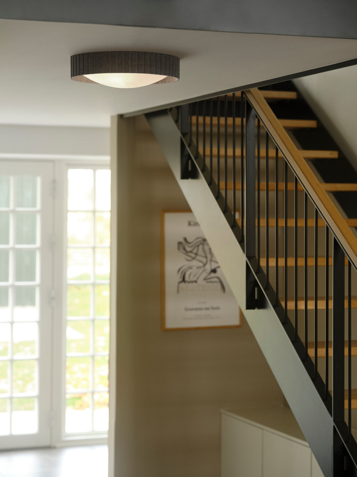 Mise en ambiance du plafonnier gris installé au plafond au-dessus d'un escalier intérieur.