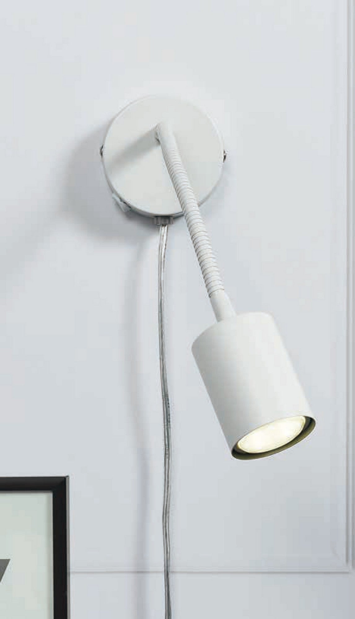 Mise en ambiance de l'applique blanche fixée au mur, près d'un cadre noir