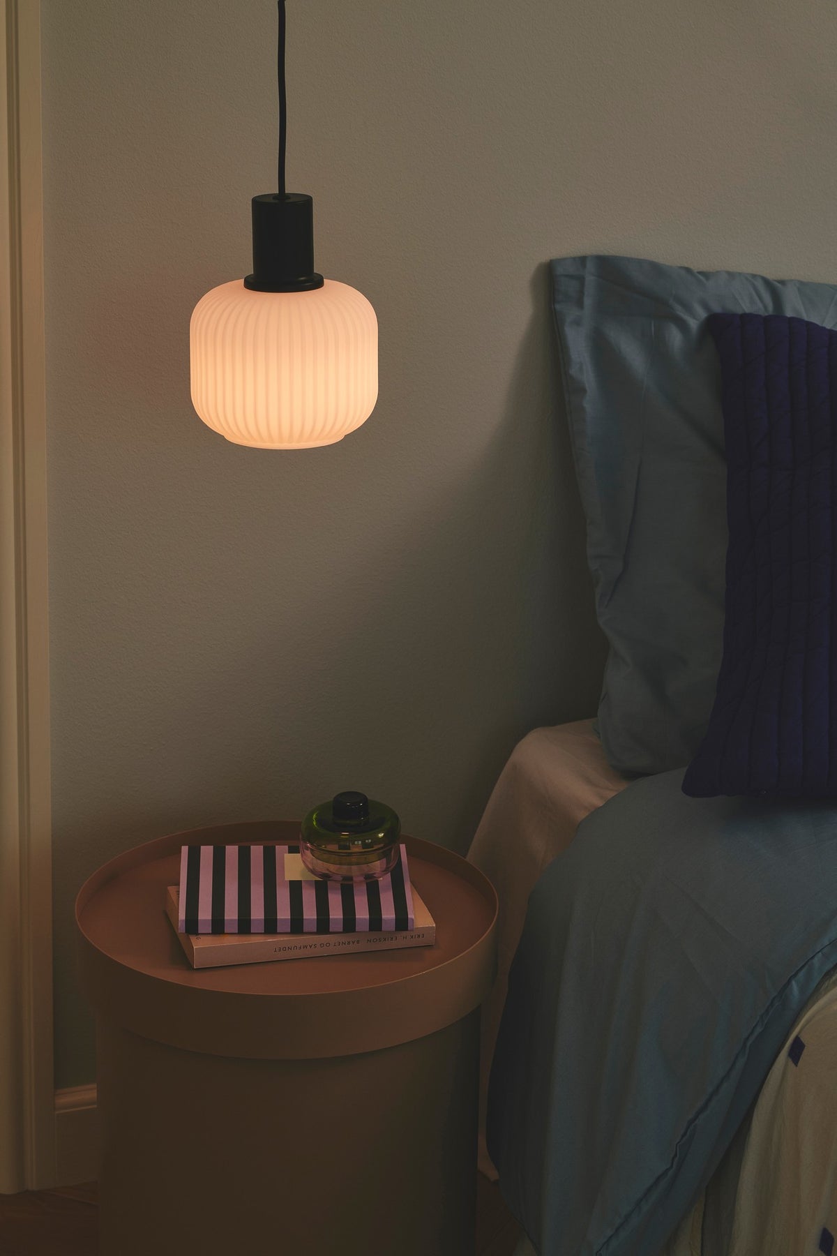 Mise en ambiance nocturne : suspension allumée au-dessus d'une table de chevet