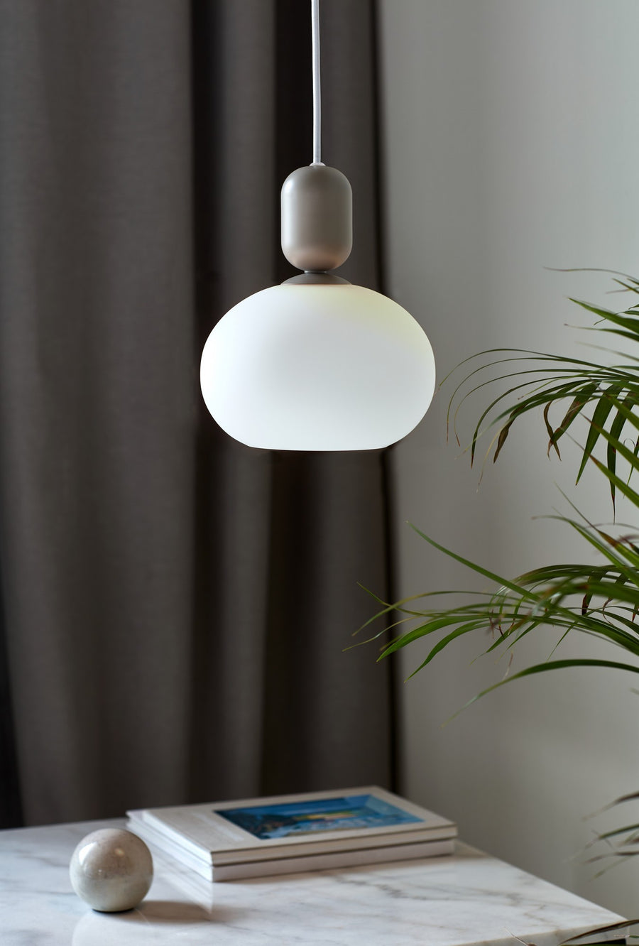 Suspension allumée suspendue au-dessus d'une table en marbre avec plante verte