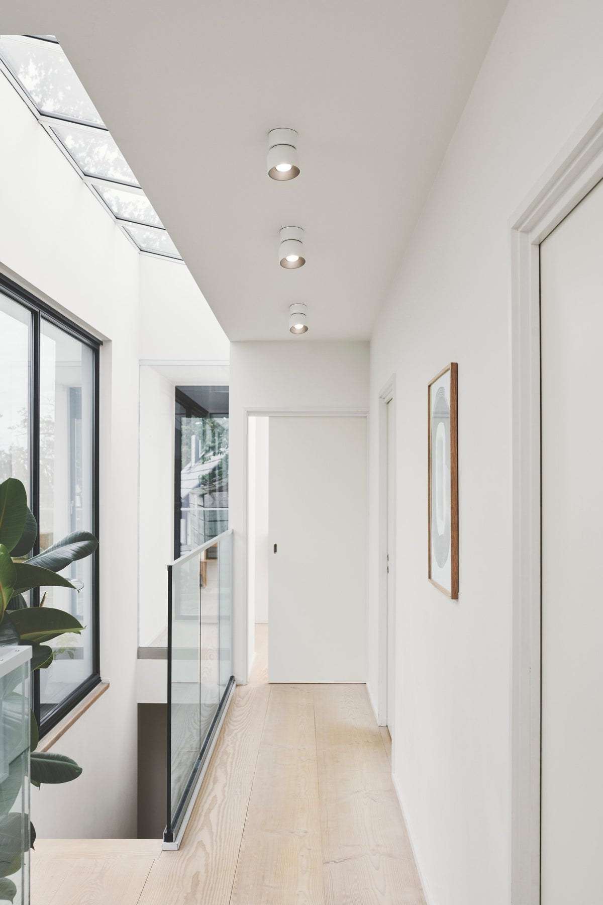 Mise en ambiance dans un couloir clair, trois spots blancs alignés au plafond