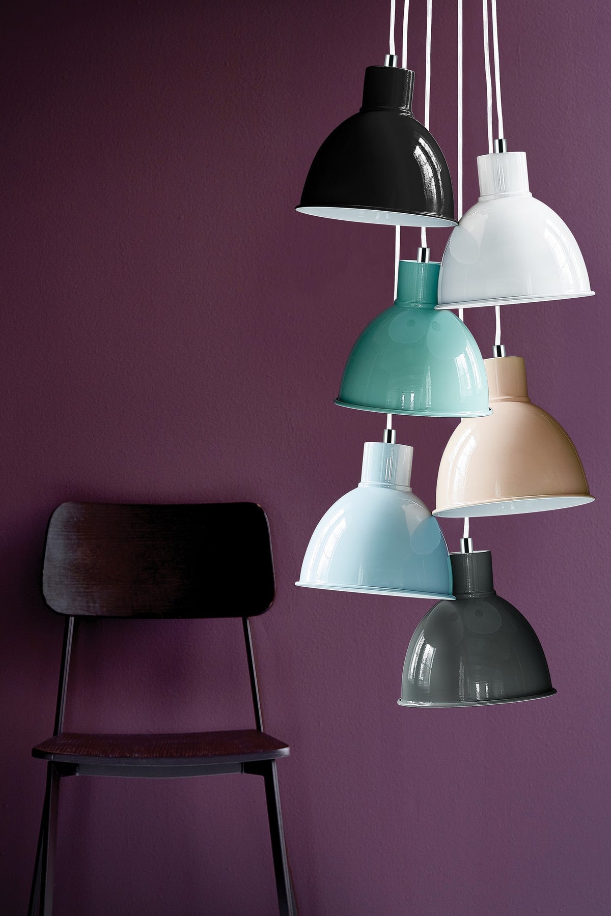 Six suspensions colorées suspendues devant un mur violet avec une chaise noire