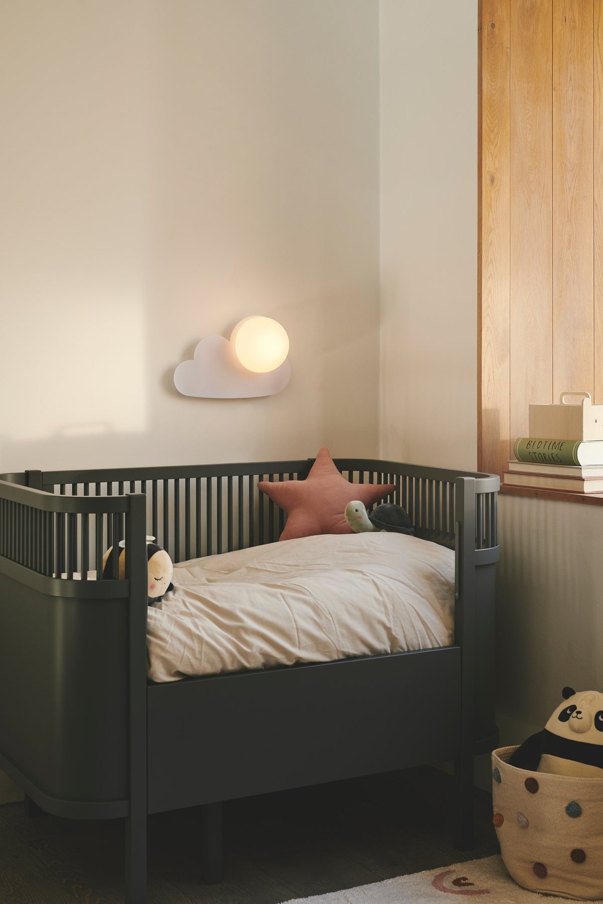 Mise en ambiance dans une chambre d'enfant avec lit à barreaux et peluches