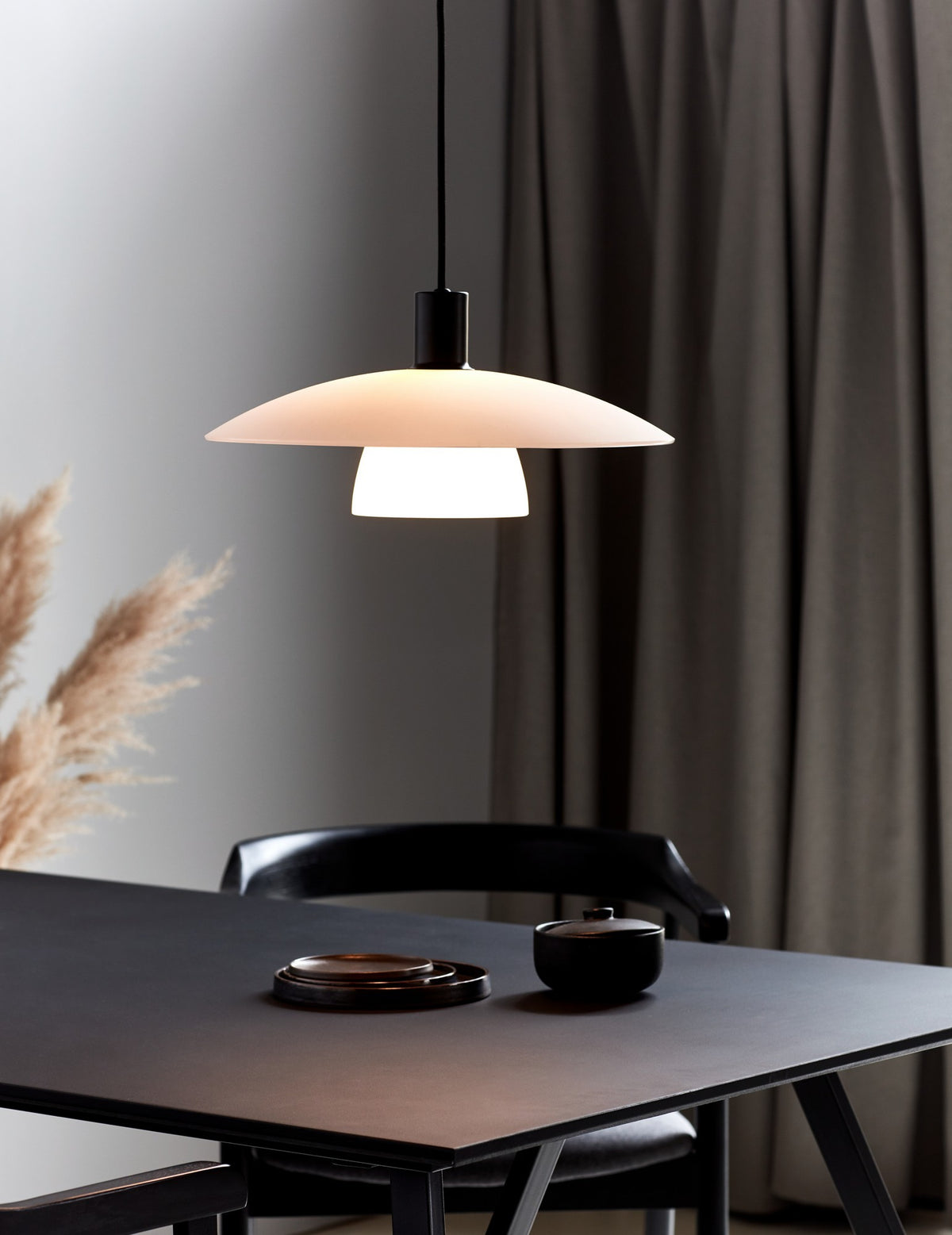 Mise en ambiance au-dessus d'une table noire, luminaire allumé dans un intérieur