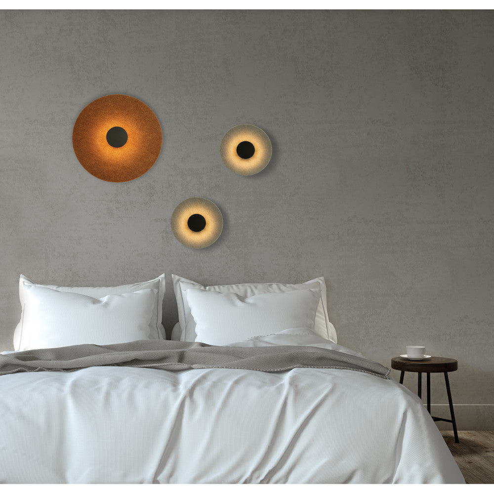 Mise en ambiance de trois appliques murales rondes au-dessus d'un lit