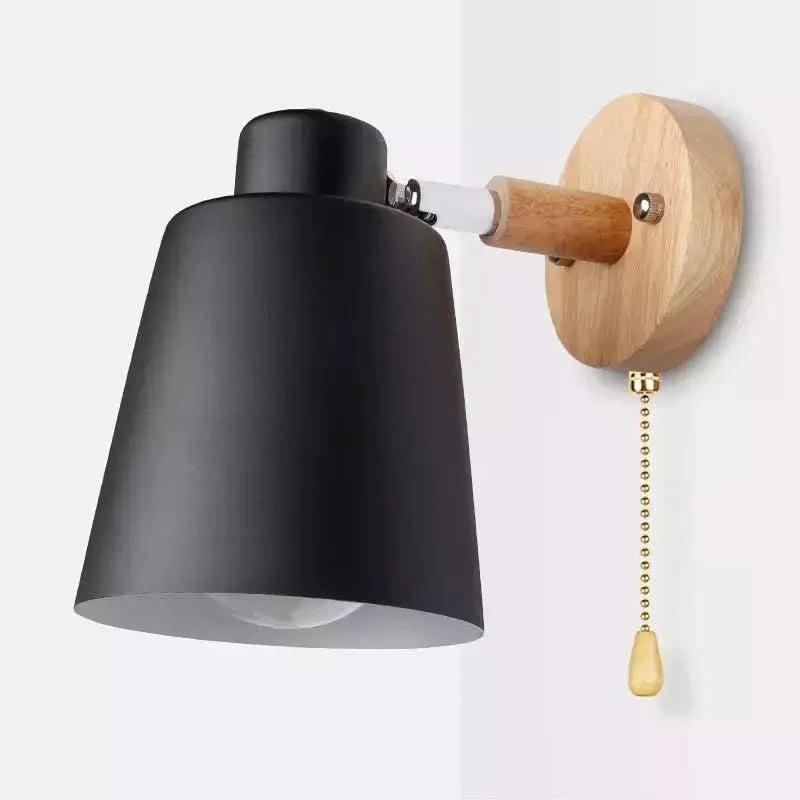 Détail de l'applique noire mate, chaînette dorée et fixation ronde en bois clair.