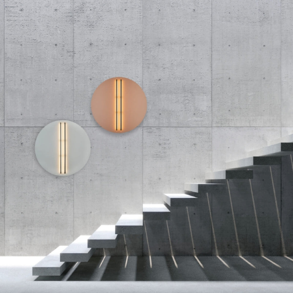 Mise en ambiance sur mur béton, deux appliques allumées près d'un escalier