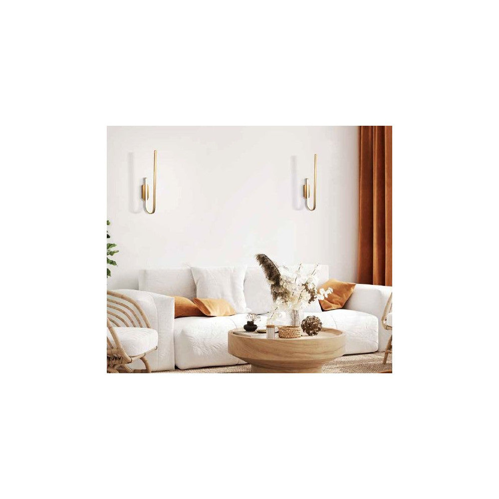 Mise en ambiance salon : deux appliques dorées éclairant un canapé blanc et une table basse