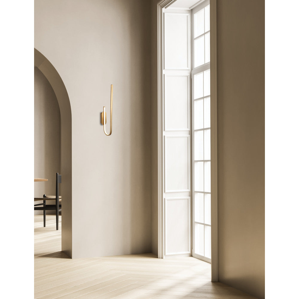 Applique murale dorée installée dans une entrée beige près d'une fenêtre