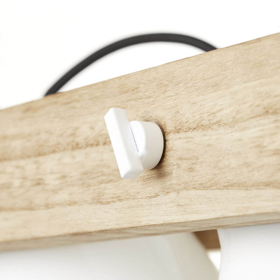 Détail rapproché du cabochon blanc fixé sur la traverse en bois clair