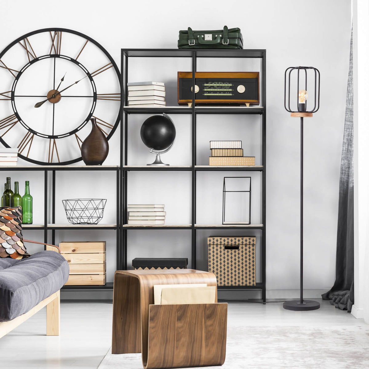 Lampadaire placé devant une grande étagère noire garnie d'objets décoratifs