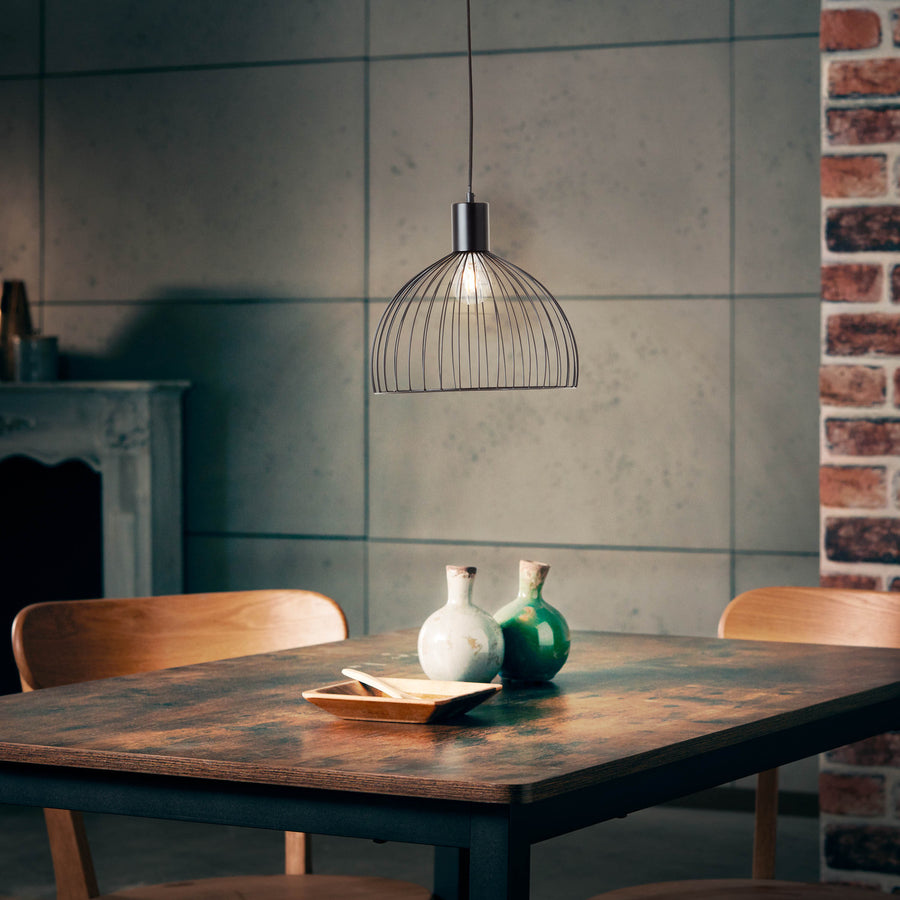 Vue plus large de la pièce, table en bois, mur béton et brique, luminaire suspendu.