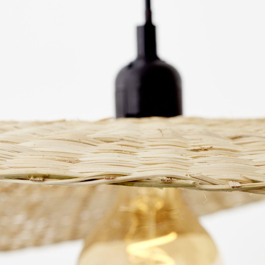 Gros plan sur la texture tressée du bambou et l'ampoule chaude en dessous.