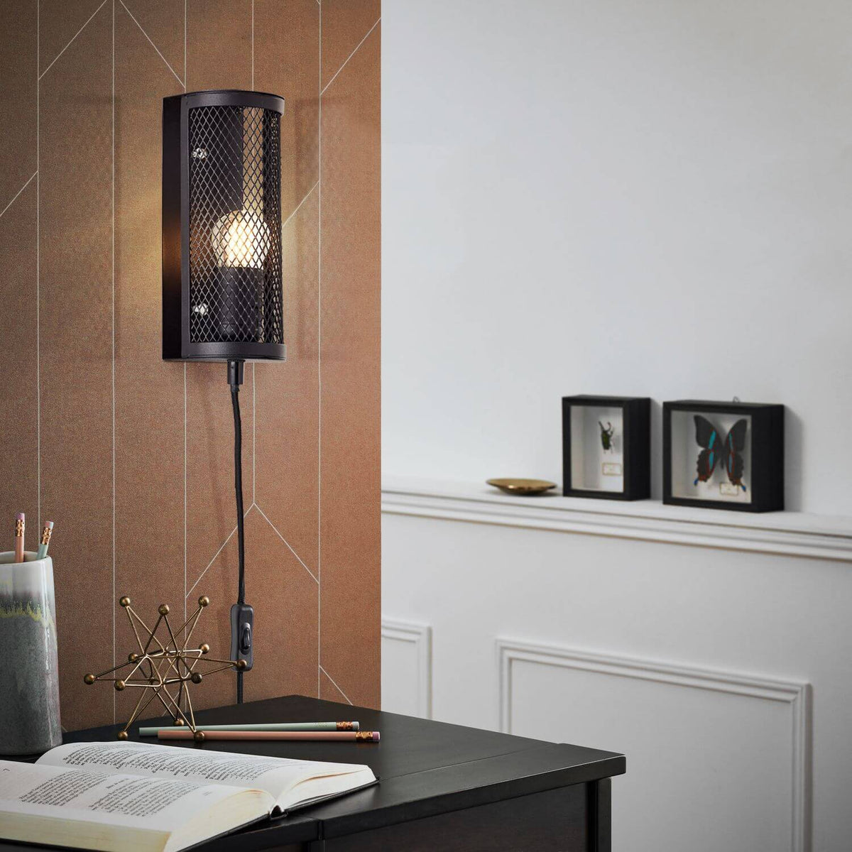 Mise en ambiance de l'applique sur un bureau, avec livre ouvert et cadres décoratifs