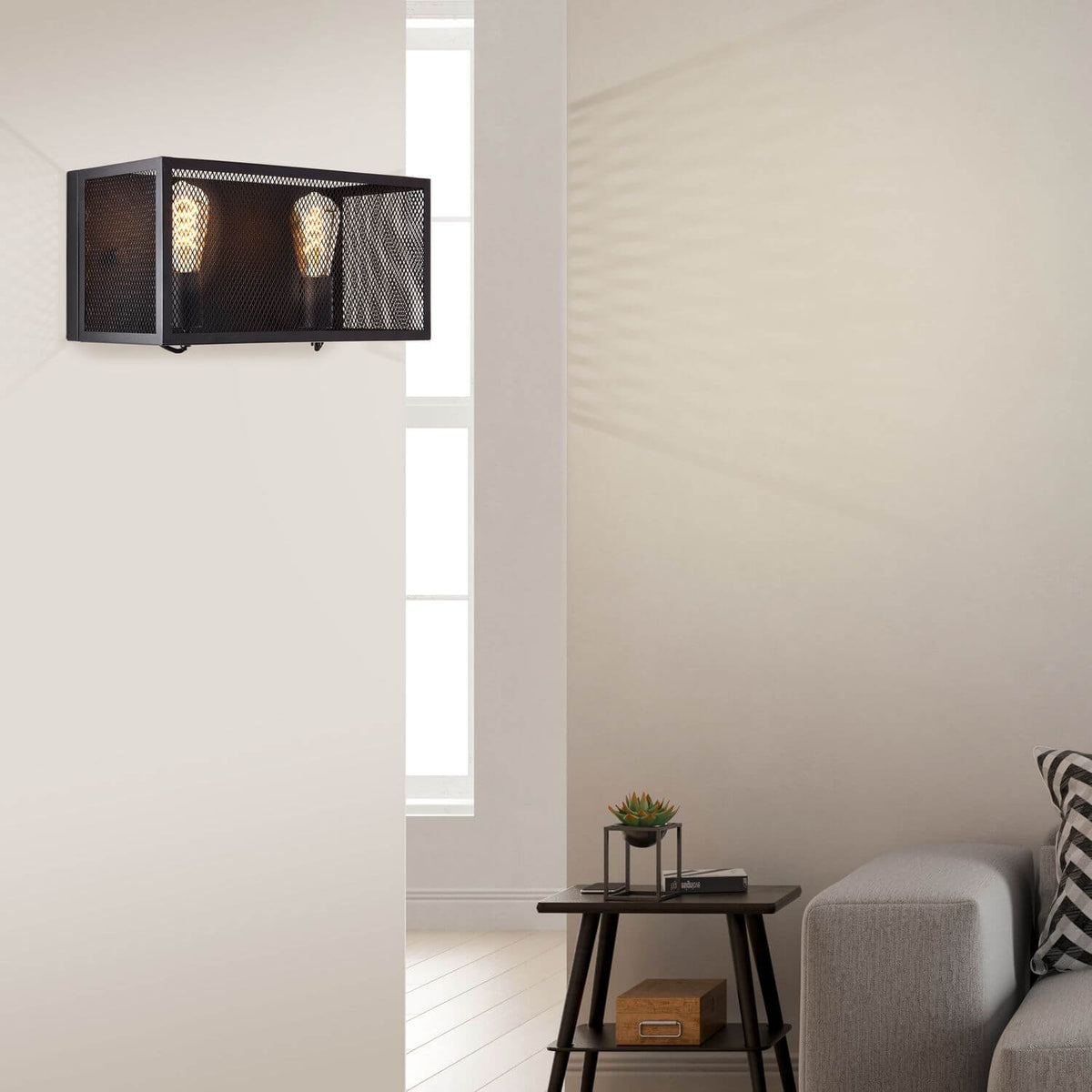 Mise en ambiance avec l’applique murale allumée au-dessus d’une table basse et d’un canapé.