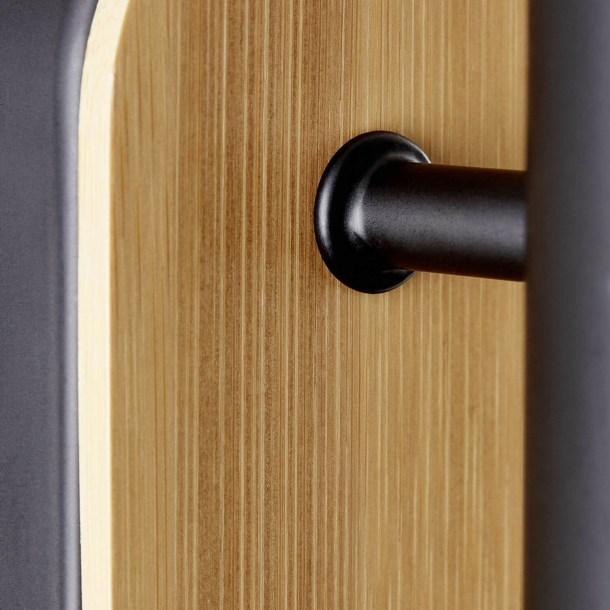 Détail de la finition avec rainures du bois clair et fixation noire mate.
