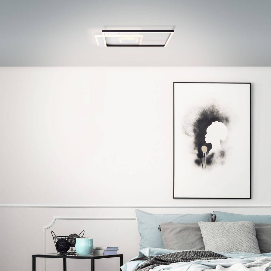 Ambiance chambre avec plafonnier allumé au-dessus du lit et d'une affiche.