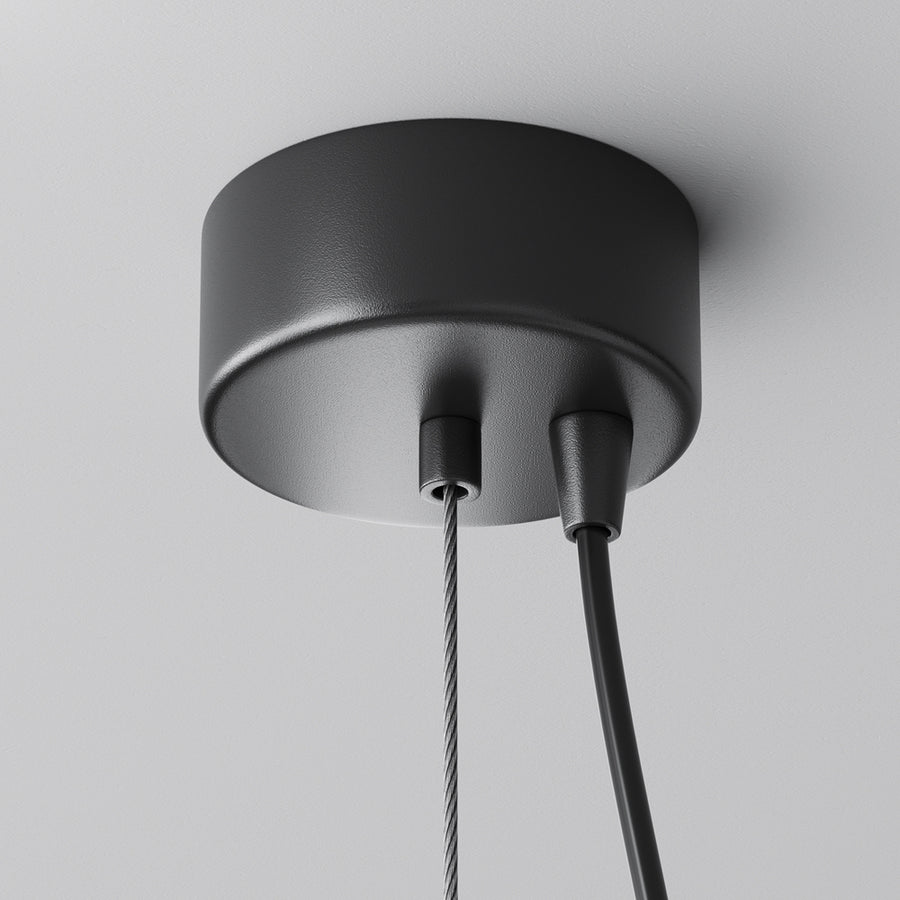 Détail de la rosace noire fixée au plafond avec câble textile et acier