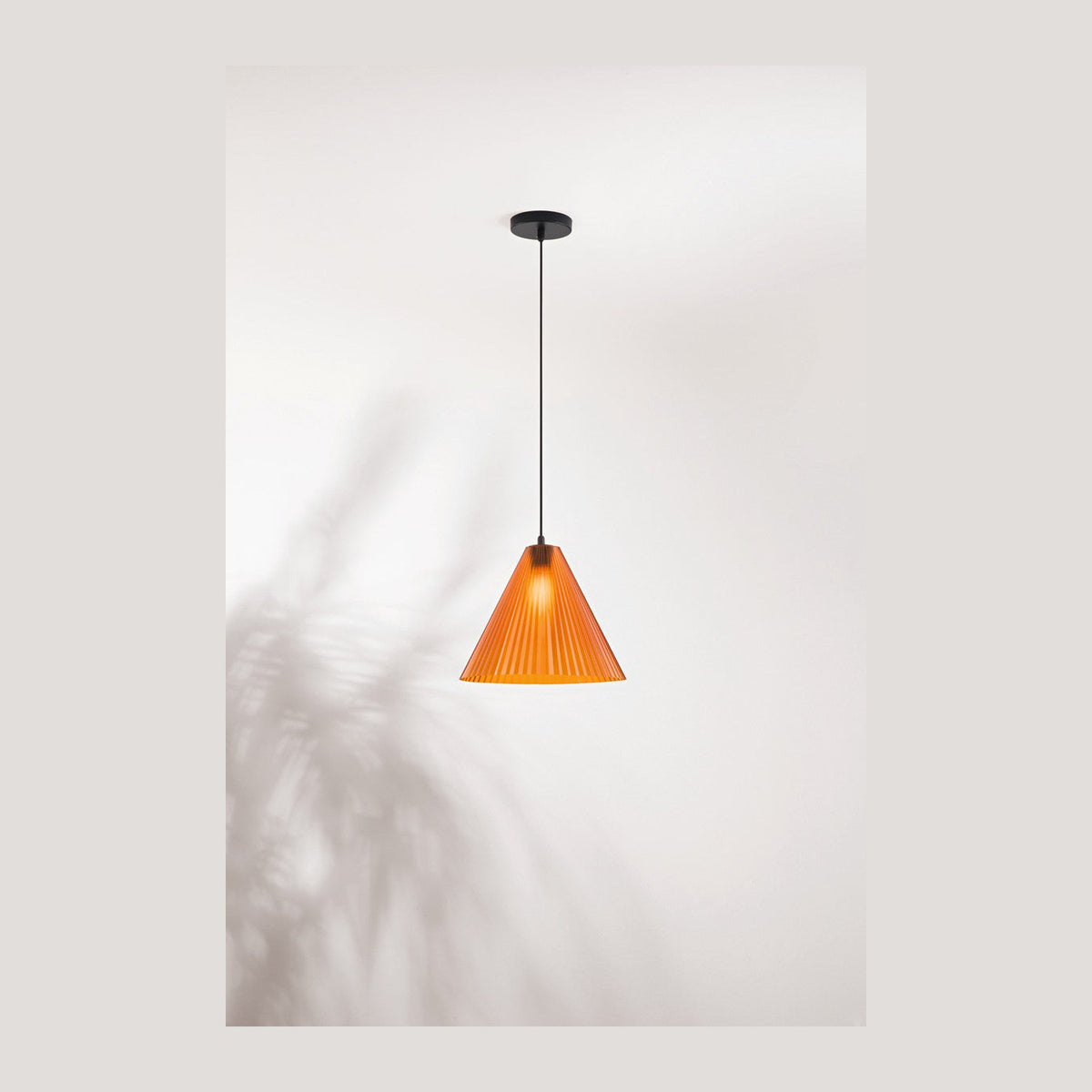 Suspension en verre ambré côtelé, vue de face avec ombres de feuillage