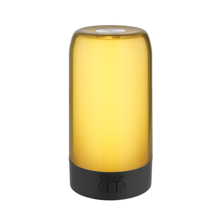 Lampe à poser cylindrique noire, base avec boutons, éclairage jaune ambré, fond blanc.