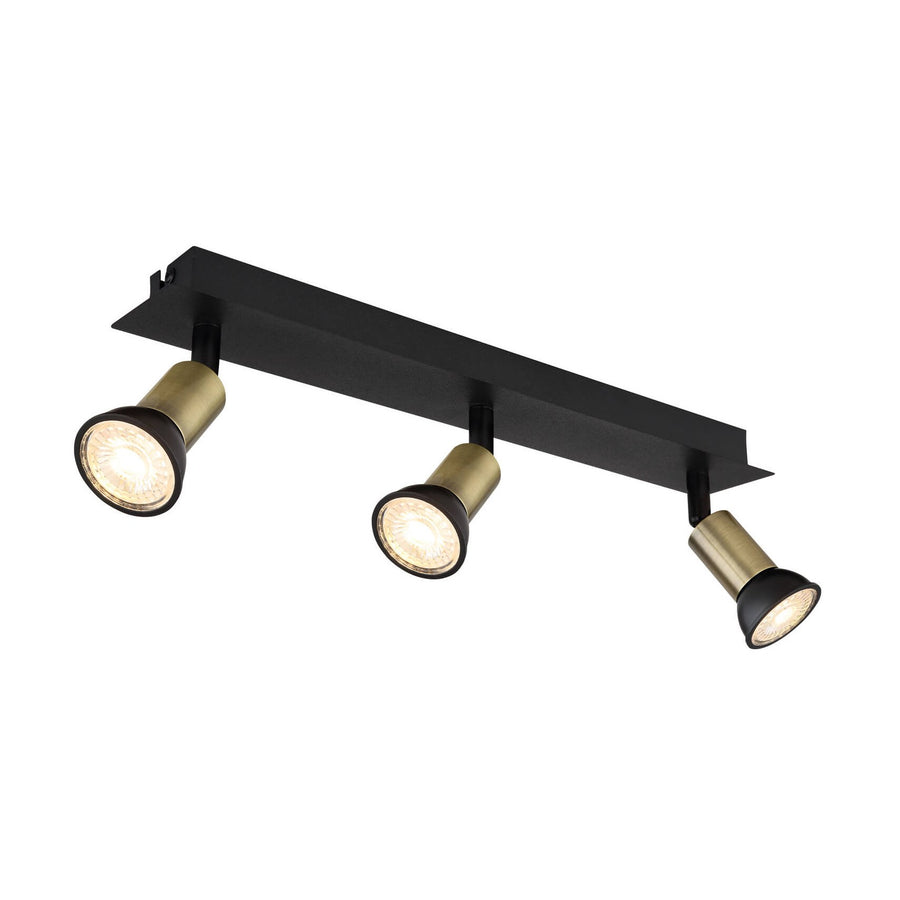 Vue de trois quarts d'un spot plafond noir mat à trois têtes orientables en laiton.